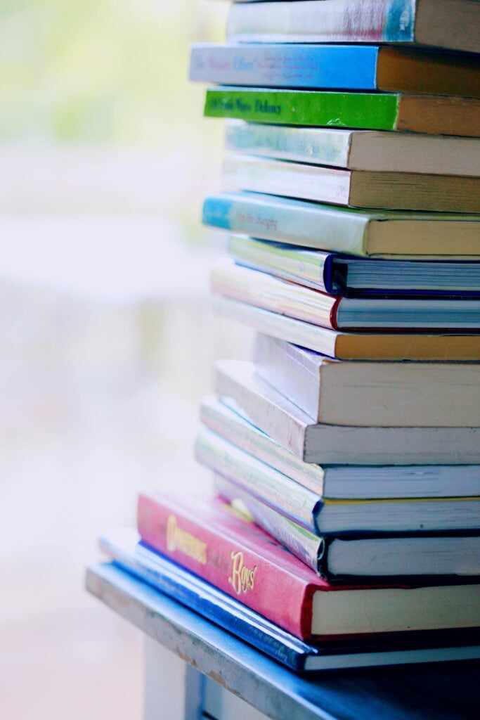 pexels-photo-1148399-1148399 A tall stack of colorful hardcover books on a table indoors, perfect for library-themed concepts.